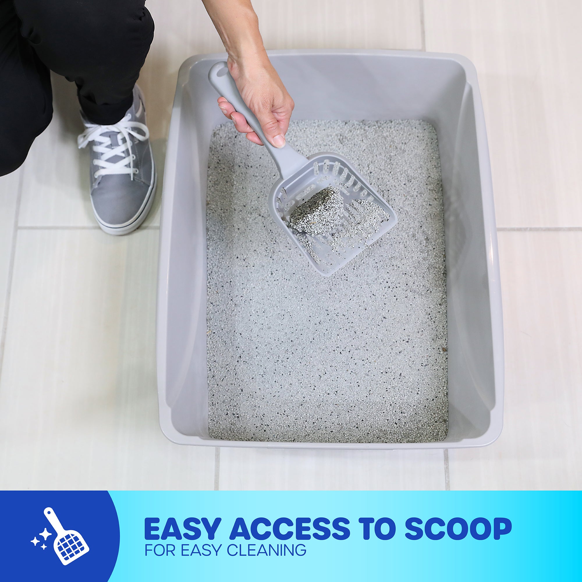 A person wearing gray sneakers cleans a large, gray Petmate Basic Litter Box made from EcoTech™ resin using a scooper. The open-top design offers easy access. A blue banner states: Easy access to scoop for easy cleaning.