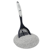 The Petmate Ultimate Litter Scoop, designed with a paw print pattern and an extra-long handle, stands out in a pile of finely textured gray litter. This essential cat cleaning tool efficiently gathers every bit as it fills the scoop.