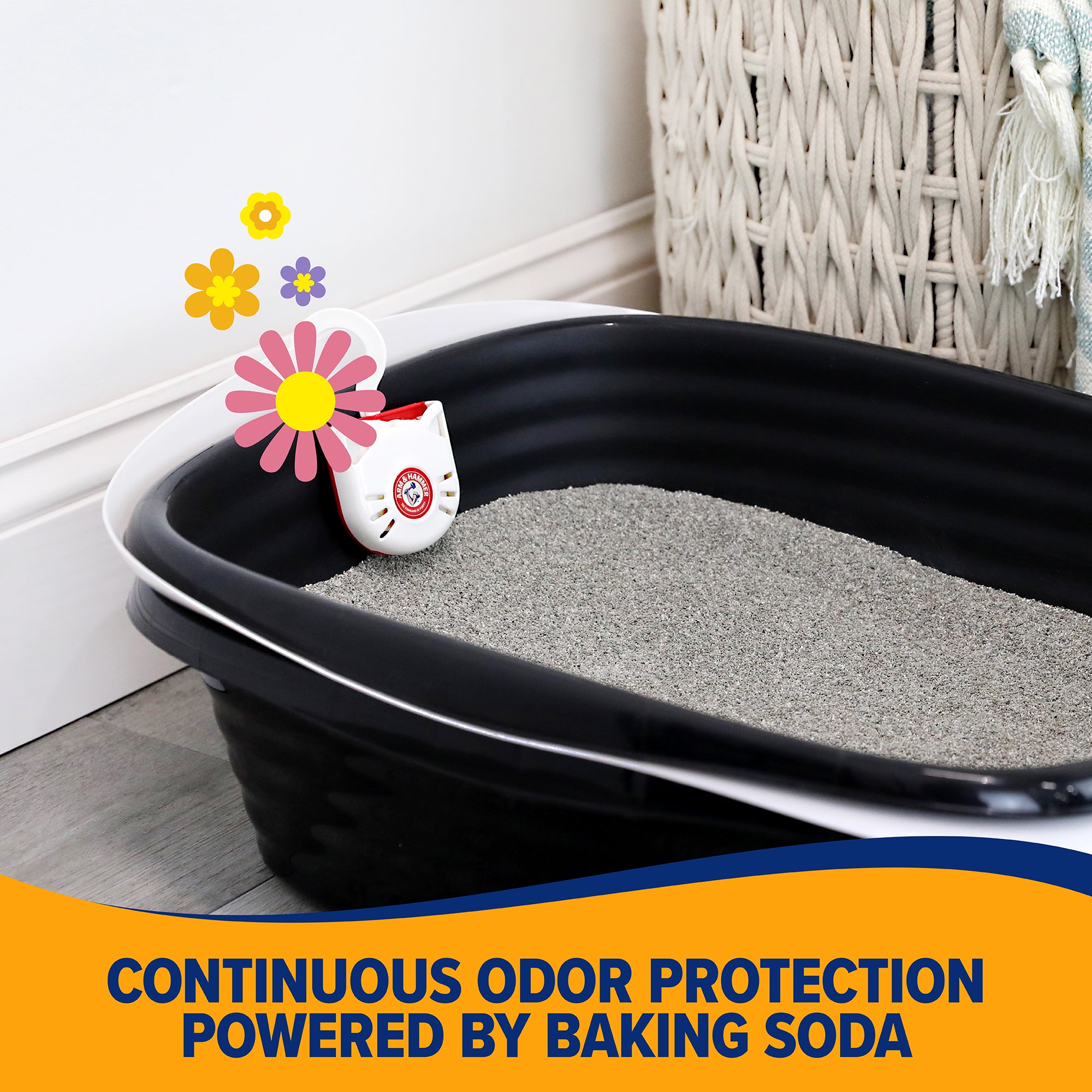 An Arm And Hammer Purrifying Pak Cat Litter Deodorizer sits in a black litter box filled with gray litter beside a woven basket. The cat-shaped air freshener features colorful flowers and offers continuous odor protection powered by baking soda.