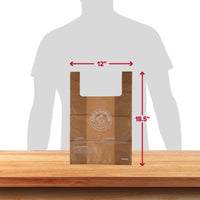 A brown plastic bag with the Arm And Hammer logo lies on a wooden surface. The Arm & Hammer Swivel Bin Pet Waste Bags measure 12 inches wide by 18.5 inches tall, ideal for pet waste disposal. A person’s silhouette in the background offers size comparison, underscoring its practicality and ease of use.