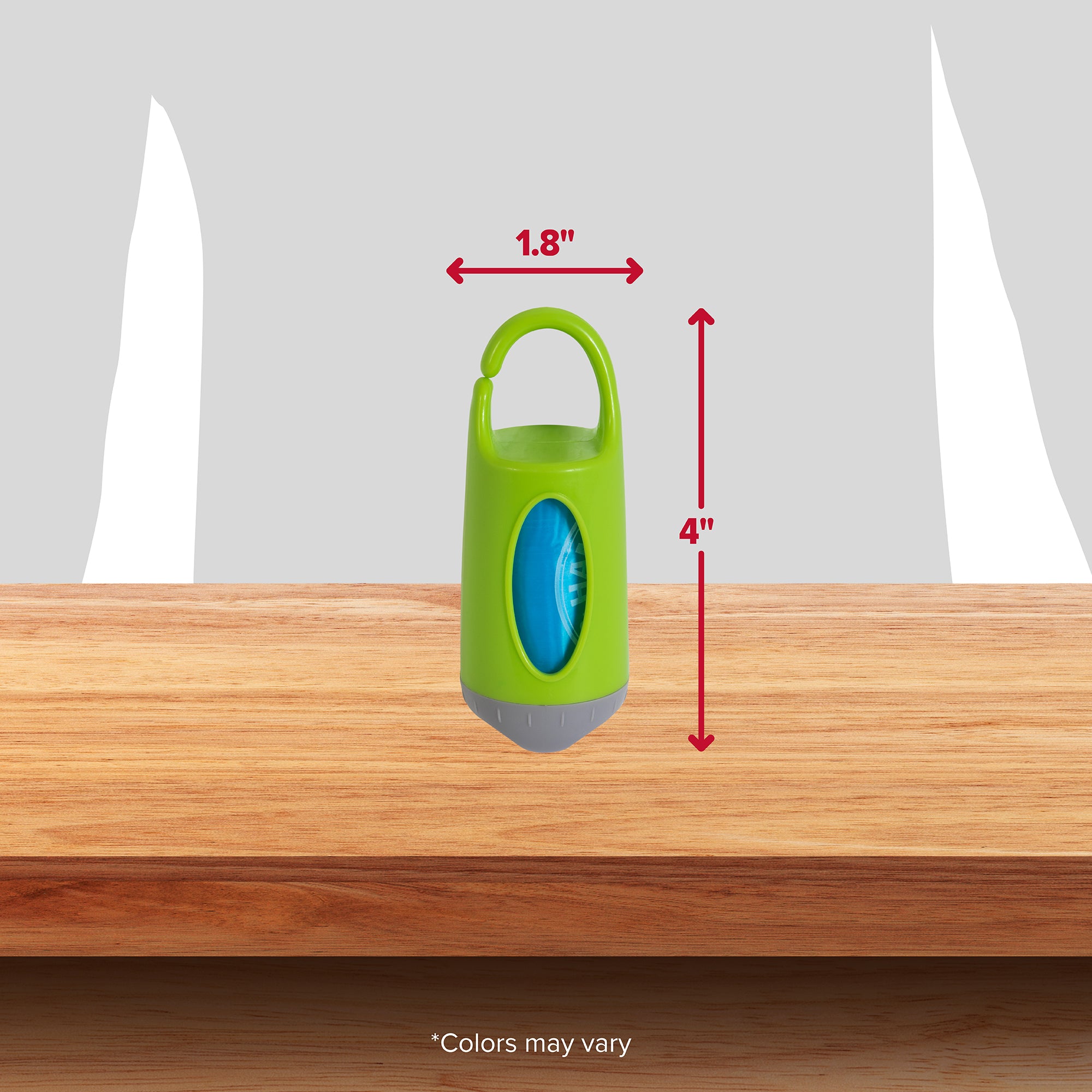 A compact green Arm & Hammer Dispenser with a top handle sits on a wooden surface. At 1.8 inches wide and 4 inches high, its ideal for storing dog waste bags with odor control. The text Colors may vary appears at the bottom.