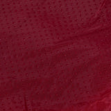 Close-up of the Aspen Pet Self-Warming Oval Lounger Pet Bed featuring a red fabric with a textured dot pattern, resembling faux lambs wool plush. The slightly wrinkled material has a subtle sheen that reflects light, creating a rich, luxurious look.