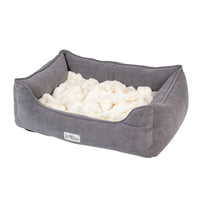The PetFusion Calming Cuddler Dog Bed by Pet Fusion is a plush rectangular bed with soft gray sides, a fluffy white interior, and slightly raised edges for anxiety relief. A small label on the front adds style while ensuring comfort for dogs.
