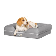 A beagle lounges on a gray PetFusion Ultimate Dog Bed With Memory Foam, featuring raised sides. This calming bed alleviates joint pain and anxiety as the relaxed pup looks aside against a white backdrop.