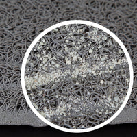 The close-up of the Petmate Litter Mat Circles Design by Petmate shows a textured gray surface with tangled loops resembling spaghetti, featuring a subtle webbed design. A circular area highlights small particles scattered over the loops, creating a speckled look against the solid black background.