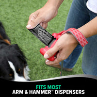 A person outdoors loads an Arm & Hammer MAX Blackout Dog Waste Bag with activated baking soda into a red dispenser, their dog at their side. Text reads, Fits Most Arm & Hammer™ Dispensers.