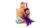 Check out the Quirky Kitty Charcuterie Board Play Mat: a vibrant set with a plush yeast jar, brie wedge, and purple fig. The board has a honey dipper design and is adorned with catnip and a big purple feather for endless feline fun.