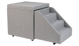 The PetFusion Multi-Purpose Pet Stairs, in premium gray with three steps and a textured fabric for durability, sits beside a soft cube-shaped ottoman, allowing pets to access higher surfaces safely.